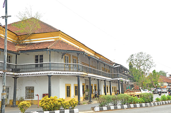 Adil Shah Palace - Historical building with a distinctive tiled roof, yellow band, white walls, and a series of dark columns supporting an upper balcony